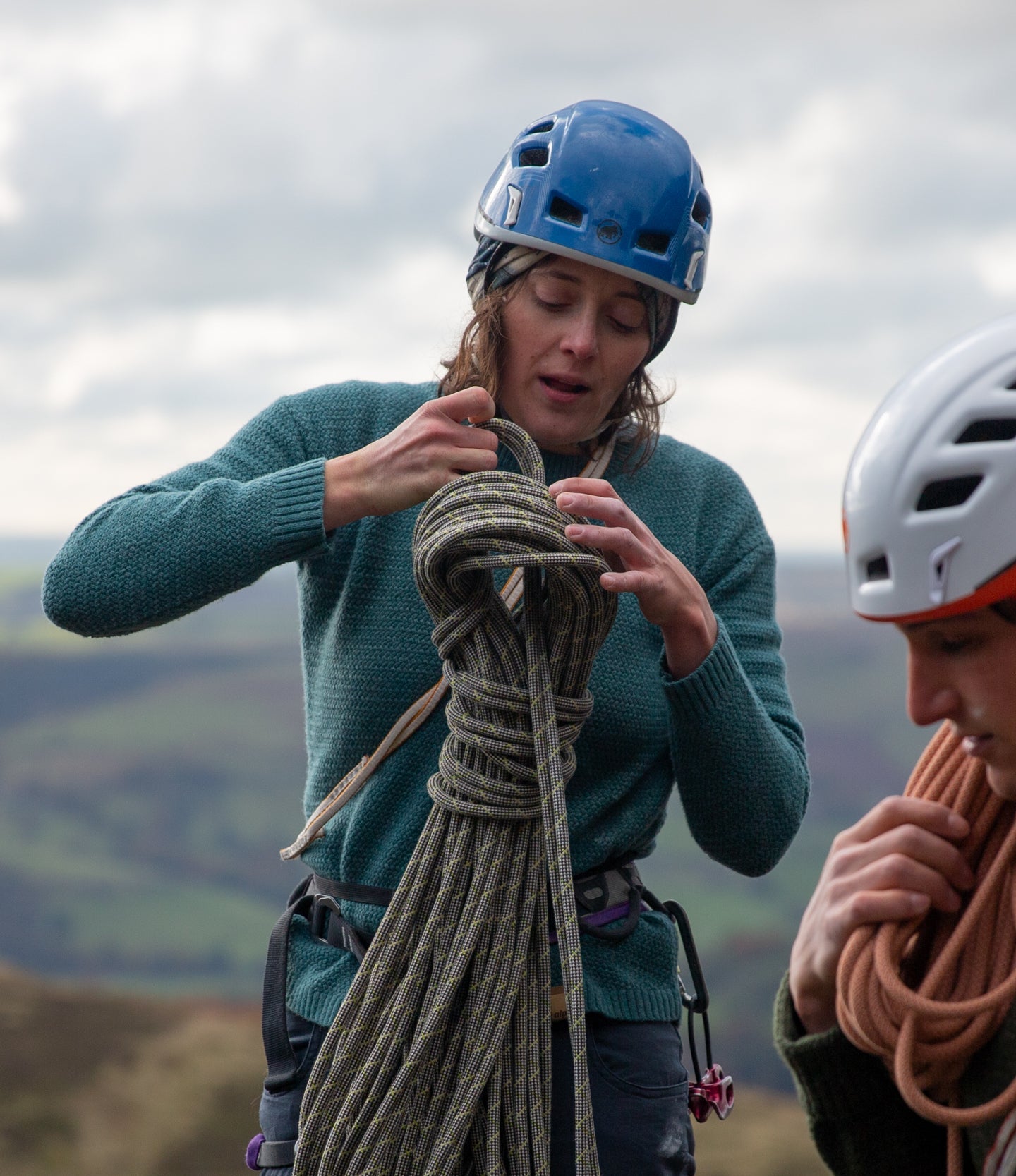 A man and a woman climbing in wool jumpers on Stanage Edge in the Peak District