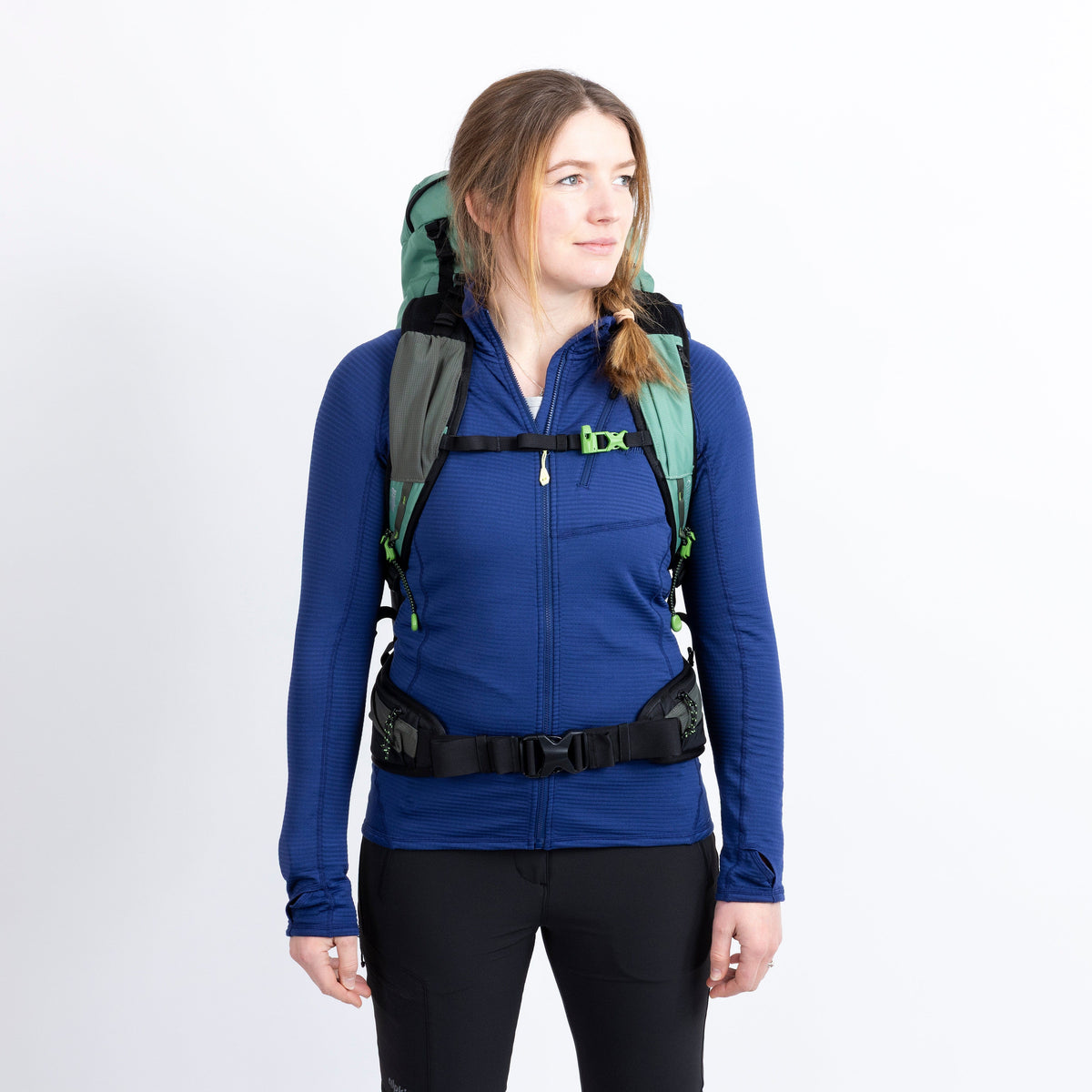 Person wearing a blue jacket and green backpack on a white background