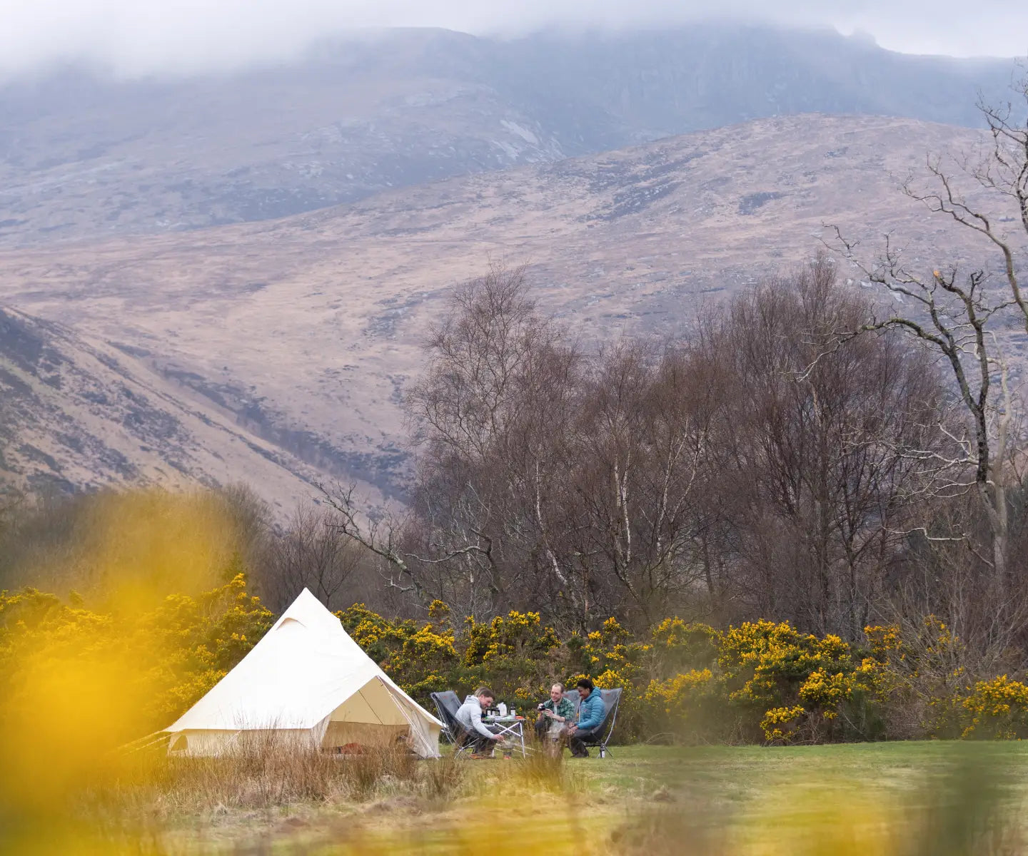 Campers sat outside a cotton teepee tent in Scotland