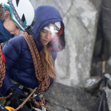 Campers sit outside a tent illuminated by LED torches