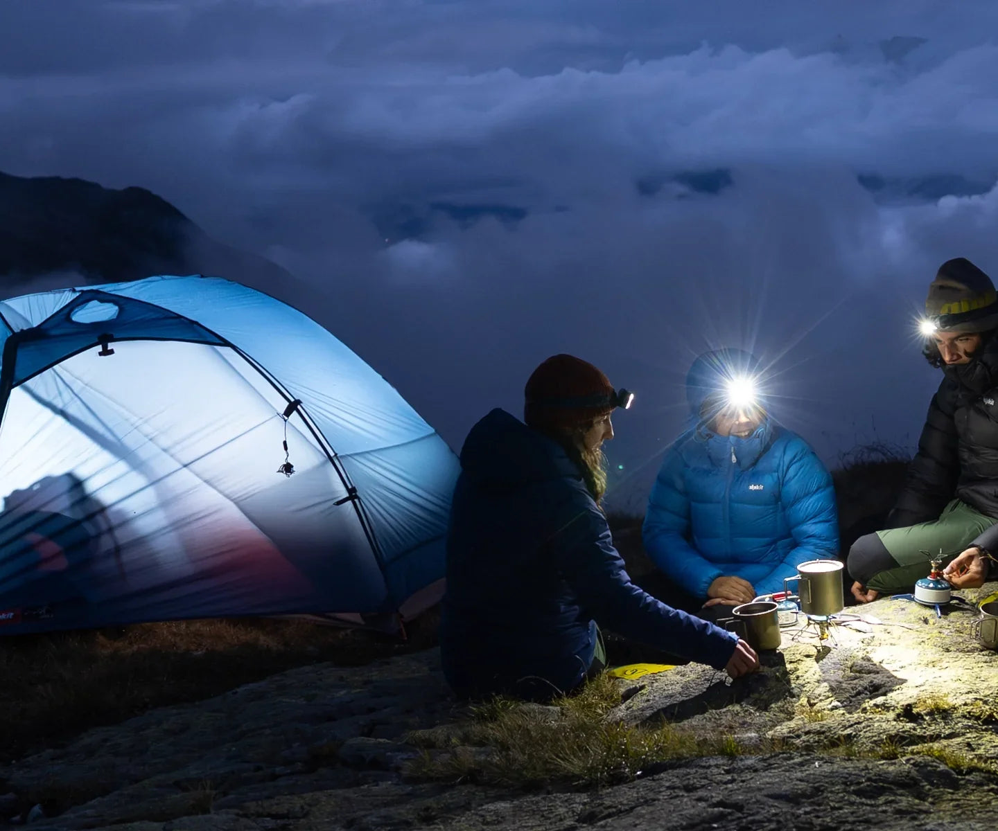 Campers sit outside a tent illuminated by LED torches