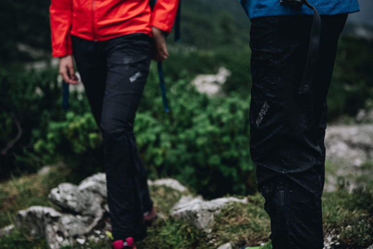 the legs of a man and woman outside in the rain wearing waterproof trousers - action