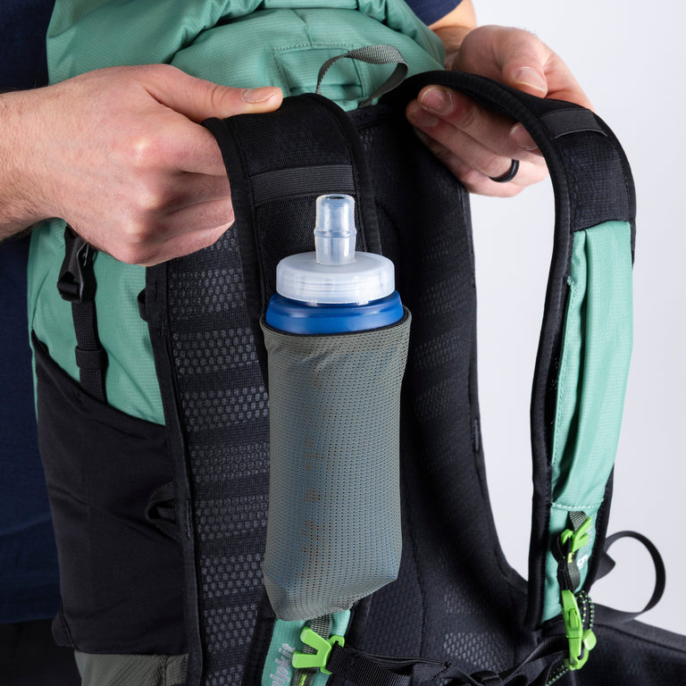 Person attaching a water bottle holder to a backpack