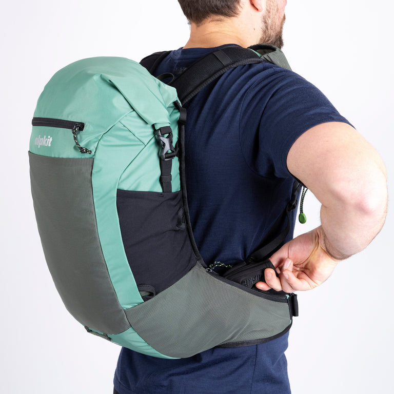 Person wearing a green and gray backpack on a white background