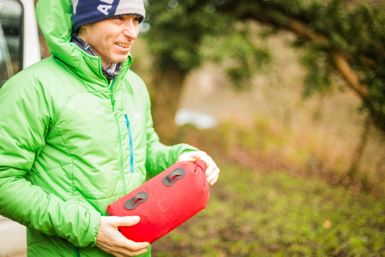 Man holding red Alpkit dry bag - action