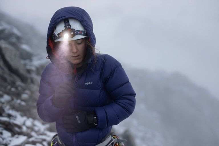 Woman using Alpkit Qark rechargeable head torch in the mist - action - closed