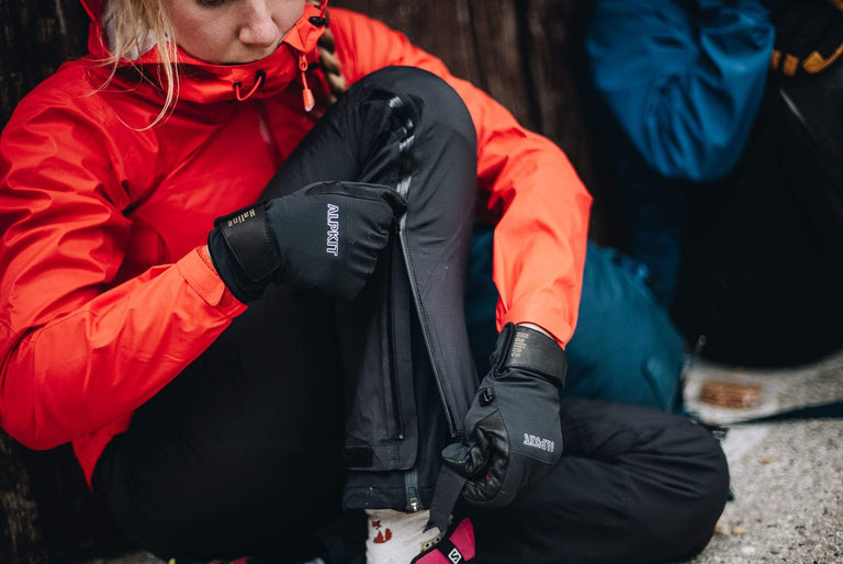 A woman sat on the floor doing up the zip on her waterproof trousers - action - closed