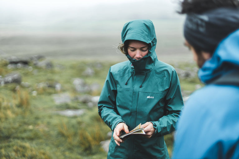 A woman wearing a green waterproof jacket on misty moorland - action - closed