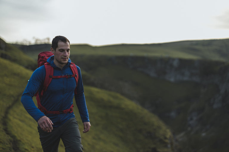 A man hiking in the Peak District in a blue lightweight fleece - action - closed