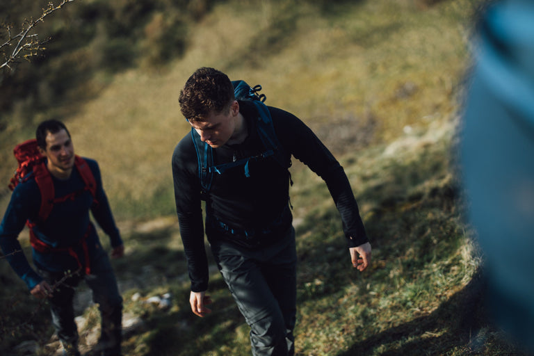 A man hiking up a steep track in the Peak District in a black hooded fleece - action - closed