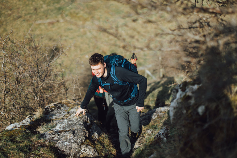 A man hiking up a steep path in the Peak District in a black hooded fleece - action - closed