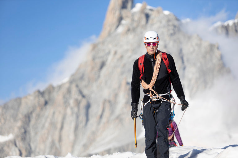 A man walking in the Alps on snow in a black Keeshond high loft fleece - action - closed