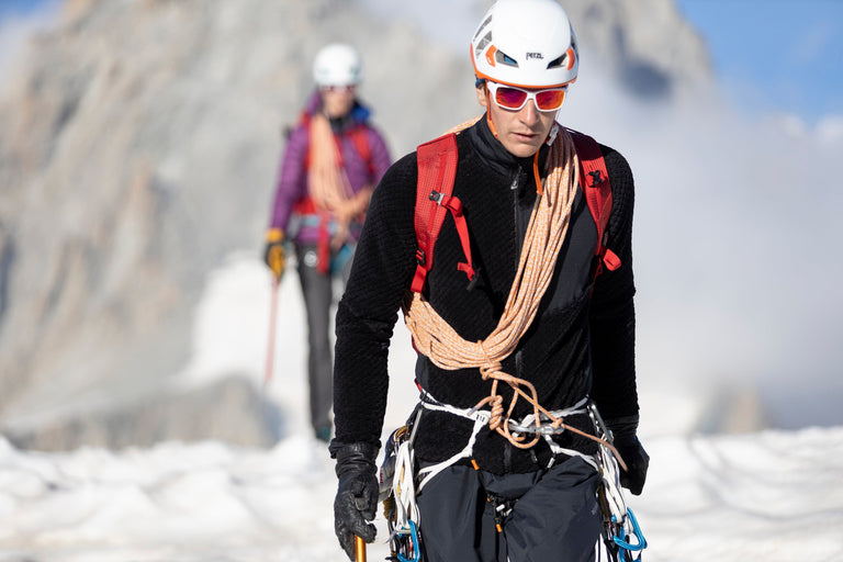 A man walking in the Alps on snow in a black Keeshond high loft fleece - action