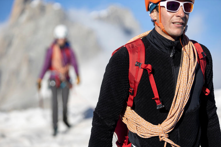 A man walking in the Alps on snow in a black Keeshond high loft fleece - action