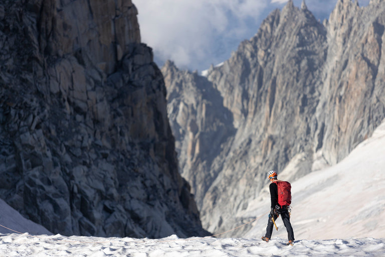 A man walking in the Alps on snow in a black Keeshond high loft fleece - action - closed