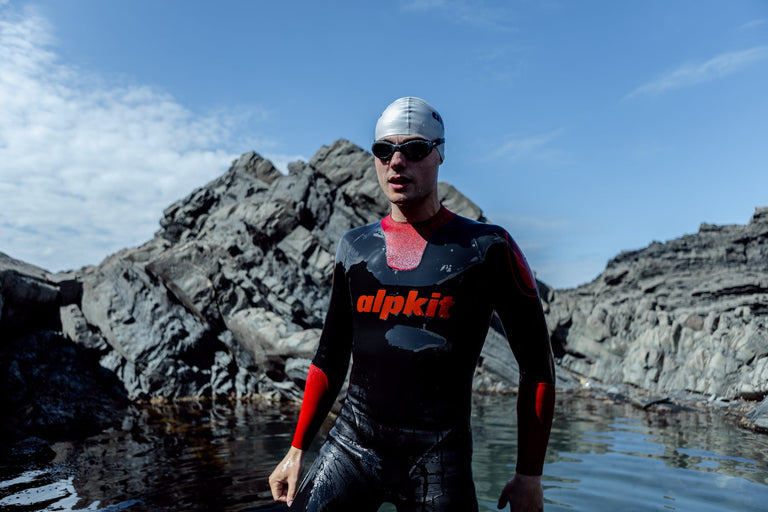 A man getting out of a coastal pool in an outdoor swimming wetsuit - action