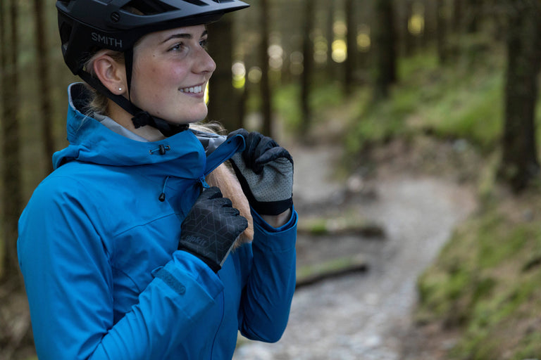 a woman wearing a blue mountain biking waterproof - action - closed