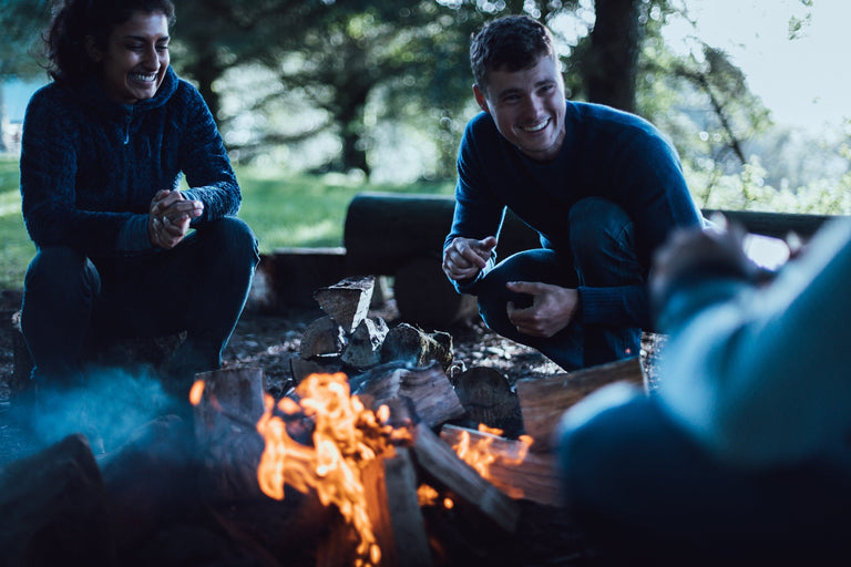 A man and a woman sat around a campfire - action