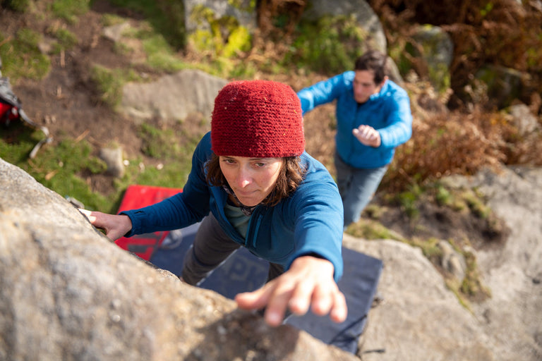 A woman bouldering in a stretchy blue fleece - action